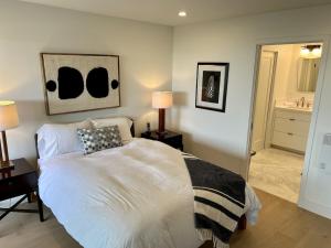 a bedroom with a white bed and a bathroom at Oceanfront Fully Remodeled 2BR 2BA, Pool, Hot Tub, Gated Parking in Solana Beach