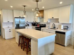 a kitchen with white cabinets and a kitchen island with stools at Oceanfront Fully Remodeled 2BR 2BA, Pool, Hot Tub, Gated Parking in Solana Beach