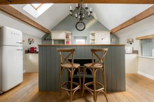 a kitchen with a dark green island with two stools at The Hay Barn in York