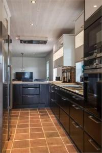 uma cozinha com armários pretos e piso em azulejo castanho em Beautiful and cosy house near the lake em Olofström