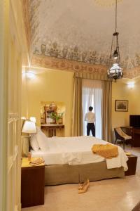 a bedroom with a large bed and a person standing in a window at Hotel Palazzo Papaleo in Otranto