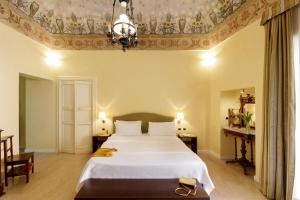 sypialnia z dużym białym łóżkiem i żyrandolem w obiekcie Hotel Palazzo Papaleo w mieście Otranto