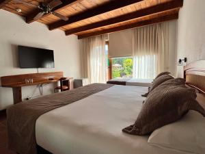 ein Schlafzimmer mit zwei Betten und einem Flachbildfernseher in der Unterkunft Hotel Pucon Green Park in Pucón + 37 Fotos