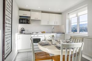 a white kitchen with a table and chairs in a room at Sunny Cottage in Brecon