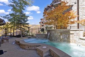 a hot tub in a backyard with a stone wall at Silver Strike Lodge #407 - 4 Bed in Park City