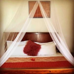 uma cama de dossel com cortinas e almofadas brancas em Epea Ocean View Top em Victoria