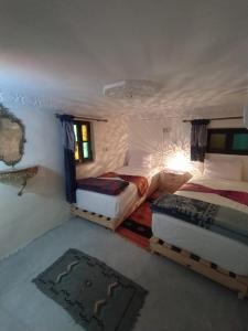 een slaapkamer met 2 bedden en een tapijt bij Dar Atlantic in Fès