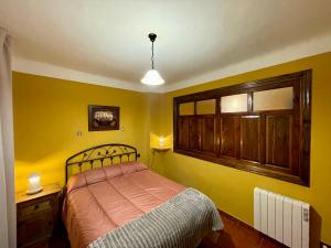 a bedroom with a bed and a yellow wall at Casa Angel in Bubión