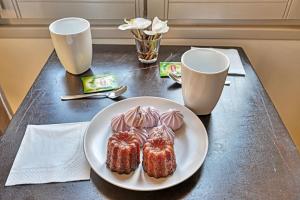 einen Tisch mit einem Teller Gebäck und zwei Tassen in der Unterkunft Au cœur des Papes, dans bâtisse de charme studios & appartements en cœur de ville in Avignon