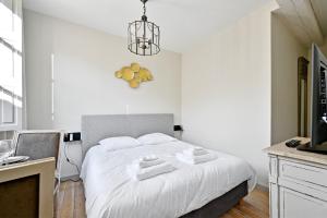 1 dormitorio con 1 cama con sábanas blancas y reloj en la pared en Au cœur des Papes, dans bâtisse de charme studios & appartements en cœur de ville en Aviñón