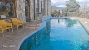 a swimming pool with chairs next to a house at Suite Roma 2 at Spa Club Bor in Velingrad
