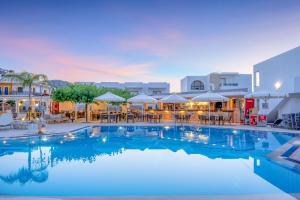 a large swimming pool with tables and umbrellas at Maria Rousse in Malia