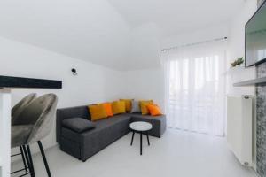 salon z szarą kanapą z pomarańczowymi poduszkami w obiekcie Duga apartmani w mieście Kragujevac