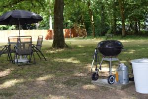 a grill and a table with a chair and an umbrella at ASH 2 Bedroom Lodge in Kingsnorth +1 photo