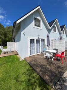 a white house with a picnic table and chairs at Domki na Marynarskiej in Grzybowo