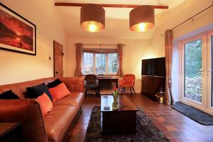 a living room with a brown leather couch and a table at Luxurious Riverside Cottage in Snowdonia National Park in Tanygrisiau
