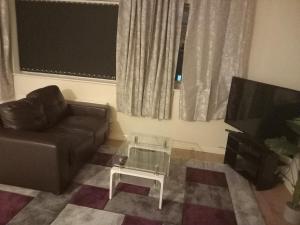 a living room with a couch and a coffee table at Lovely Shared 3 Bed Home Near The Thames in Thamesmead