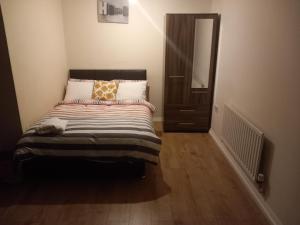 a small bedroom with a bed with a mirror at Lovely Shared 3 Bed Home Near The Thames in Thamesmead