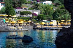 una piscina d'acqua con sedie e ombrelloni di Gardenia Mare a Ischia