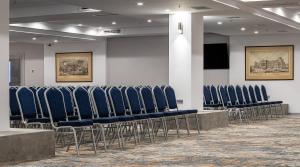 a row of blue chairs in a room with a screen at Premier Hotel Dnister in Lviv