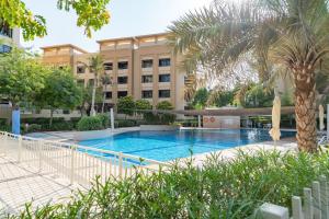 een zwembad voor een gebouw met een palmboom bij Vogue - The Greens and Views in Dubai