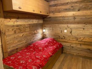 a small cabin with a red bed in the corner at Appartement La Clusaz, 3 pièces, 6 personnes - FR-1-459-28 in La Clusaz