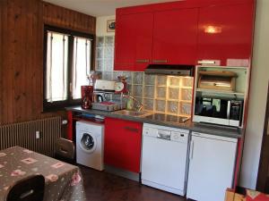 a kitchen with red cabinets and a washer and dryer at Appartement La Clusaz, 3 pièces, 6 personnes - FR-1-459-54 in La Clusaz