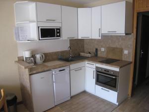 una pequeña cocina con armarios y electrodomésticos blancos en Studio cabine au centre, balcon sud, parking, proche pistes et commerces - FR-1-459-89, en La Clusaz