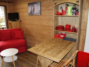 Una sala de estar con una mesa y una silla roja. en Studio rénové au cœur de La Clusaz, proche pistes et commerces - FR-1-459-115, en La Clusaz