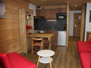 a kitchen and living room with a table and a red couch at Studio La Clusaz, 1 pièce, 2 personnes - FR-1-459-115 in La Clusaz