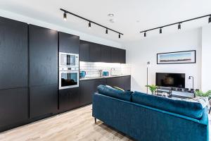 a living room with a blue couch and a kitchen at Icon Tower Flat VII in London