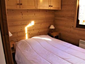 um quarto com uma cama branca numa parede de madeira em Appartement Saint-Jean-de-Sixt, 2 pièces, 4 personnes - FR-1-459-165 em Saint-Jean-de-Sixt