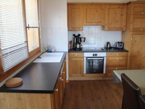 eine Küche mit Holzschränken und einer schwarzen Arbeitsplatte in der Unterkunft Appartement 3 chambres avec balcon en centre village, proche La Clusaz et Le Grand Bornand - FR-1-459-161 in Saint-Jean-de-Sixt + 5 Fotos