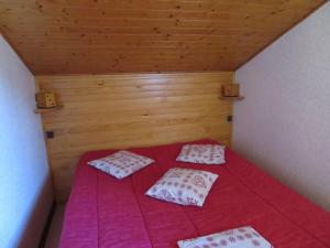 ein kleines Bett mit roten Laken und Kissen in einem Zimmer in der Unterkunft Duplex ensoleillé et calme, proche des pistes - Parking et casier à skis inclus - FR-1-459-187 in Saint-Jean-de-Sixt