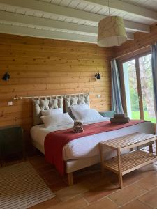 1 dormitorio con 1 cama grande y pared de madera en Gîte des Etangs, en Glanville
