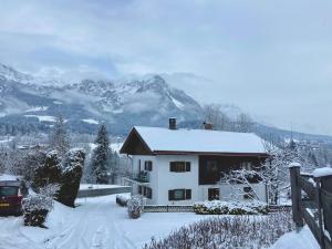 une maison recouverte de neige avec des montagnes en arrière-plan dans l'établissement D&D Apartment, à Scheffau am Wilden Kaiser