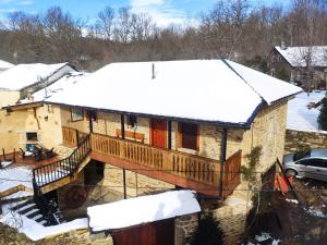 a house with a deck in the snow at Casa la ti María la viuda in Riego de Lomba