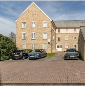 three cars parked in front of a large brick building at Papworth apartment in Papworth Everard