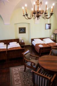 a bedroom with two beds and a table and a chandelier at Zamek w Baranowie Sandomierskim in Baranów Sandomierski