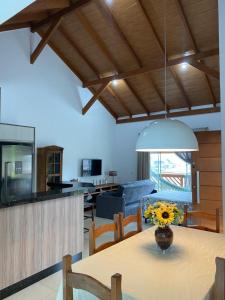 a kitchen and dining room with a table with a vase of flowers at Studio Recanto Beach Itapema in Itapema