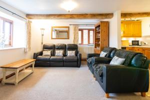 a living room with two leather couches and a table at The Oast House - farm stay apartment set within 135 acres in Bromyard