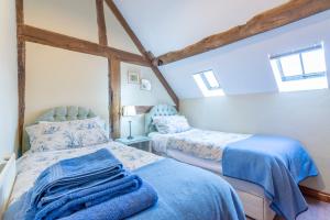 a bedroom with two beds with blue sheets at The Oast House - farm stay apartment set within 135 acres in Bromyard