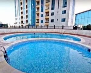 a large blue swimming pool in front of a building at Superbe studio spacieux et ensoleillé in Ajman 