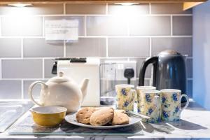 a counter with a plate of cookies and coffee mugs at The Oast House - farm stay apartment set within 135 acres in Bromyard