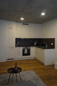 a kitchen with white cabinets and a table in a room at Schönes Neubau Serviced-Apartment mit Parkplatz in Bruchsal