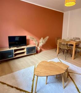 ein Wohnzimmer mit einem Flachbild-TV und einem Tisch in der Unterkunft Vaste Appartement Rénové - Centre Ville in Bourg-en-Bresse