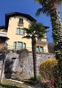 a yellow building with a palm tree in front of it at Villa Silvana in Perledo