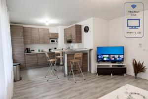 eine Küche und ein Wohnzimmer mit einem TV und einer Theke in der Unterkunft Tout confort à Massy - Parking / TGV et RER B&C in Massy