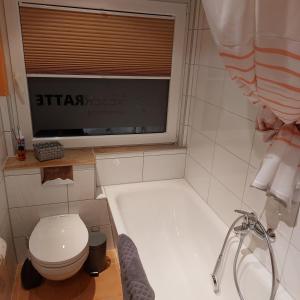 baño con bañera, aseo y ventana en Ferienwohnung WESERRATTE en Hameln