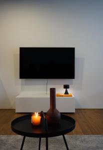 un soggiorno con TV e tavolo con candela di Schönes Neubau Serviced-Apartment mit Parkplatz a Bruchsal